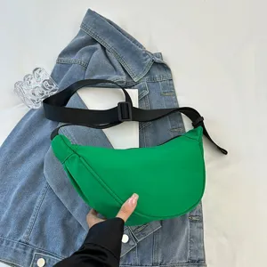 Vibrant green minimalist crescent dumpling bag shown on a casual denim jacket background
