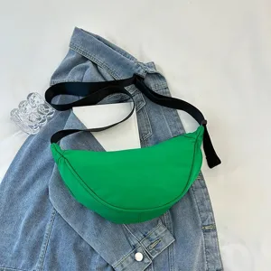 Minimalist vibrant green nylon crescent crossbody bag shown in a casual lifestyle detail view