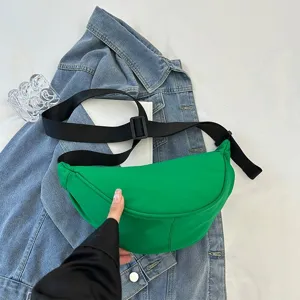 Close-up of a vibrant green solid color dumpling crossbody bag on a denim jacket