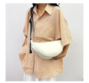 Detailed close-up showing a white minimalist crescent crossbody dumpling bag on a model