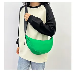 Detailed view of a bright green minimalist dumpling bag worn as a casual crossbody bag.
