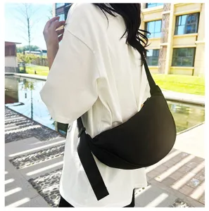 A woman wearing a black minimalist solid color dumpling crossbody bag outdoors