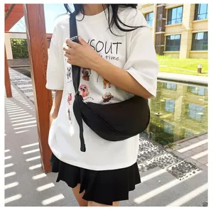Close-up of a minimalist black dumpling crossbody bag worn by a model in an outdoor setting