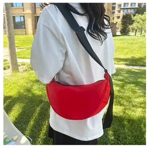 Red crescent crossbody bag styled with a white T-shirt in an outdoor setting