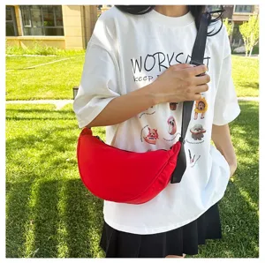 Detailed shot of a vibrant red minimalist dumpling crossbody bag styled for casual outdoor wear
