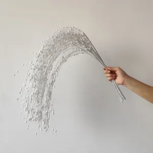 Mano che tiene rami di salice bianchi glitterati con bacche di schiuma per decoro