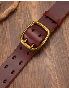 Macro detail of a vintage washed cowhide leather belt with brass double prong buckle