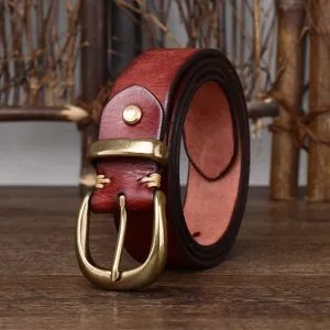 Detail of a vintage dark red leather belt with a brass pin buckle on a wooden surface.