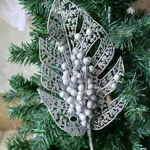 Silver glitter monstera leaf and berry branch Christmas tree decoration detail view closeup.