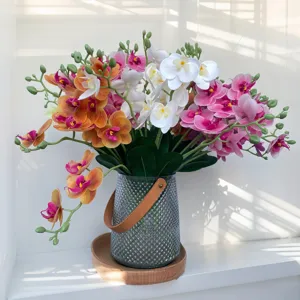 Artificial Phalaenopsis orchid flowers arrangement with glass vase and wooden base for decor.