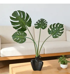Detailed close-up view of artificial monstera leaves arranged in a modern black ceramic art vase.