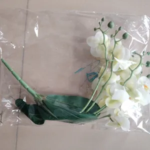 Artificial white orchid flower single stem with green leaves in clear bag packaging detail view