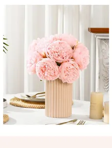 Artificial pink peony flower bouquet in ribbed vase, elegant home and wedding decor setup.