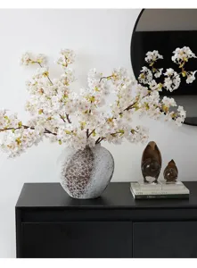 Detalle de dos ramas de flores de cerezo blancas realistas en un jarrón moderno