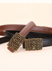 Close-up of ornate vintage gold buckles on black and brown leather belts for women.