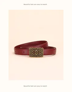 Close-up view of a vintage red leather belt featuring an ornate golden filigree buckle.