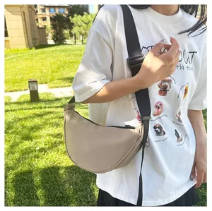 Minimalist beige crescent crossbody bag shown in a lifestyle outdoor setting detail