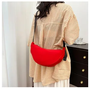 Vibrant red lightweight crescent crossbody dumpling bag styled on a person for a casual look