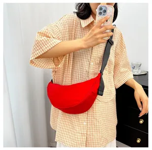 Close-up of a vibrant red crescent crossbody bag worn with a casual checked shirt