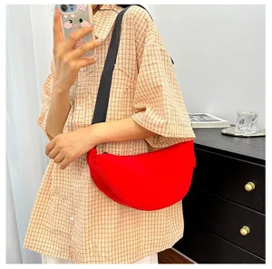Red crescent crossbody dumpling bag shown in a lifestyle setting with casual outfit