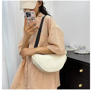 Close-up detail of a minimalist cream-white dumpling crossbody bag worn on shoulder
