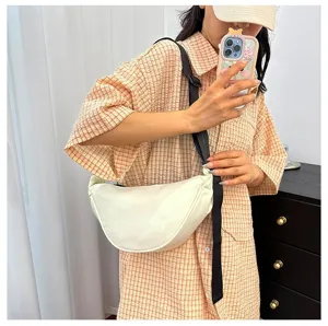 Lifestyle shot of a minimalist off-white crescent dumpling bag worn as a crossbody