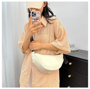 Minimalist cream crescent crossbody bag styled with casual checkered shirt.