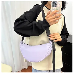 Detail shot of a minimalist purple crescent crossbody bag worn as a casual shoulder bag.
