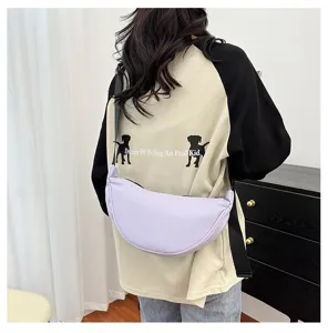 Female model wearing a light purple minimalist dumpling crossbody bag in a home setting