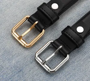 Detailed close-up of gold and silver metal buckles on black leather belts over denim fabric