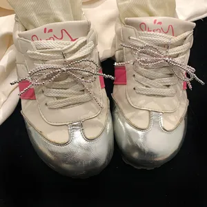 Détail de breloques de chaussures élégantes en perles en forme de nœud sur baskets.