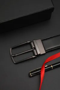 Close-up of premium black leather belt buckle with elegant gift box and red ribbon
