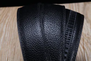 Détail d'une sangle de ceinture en cuir grainé noir avec rail à cliquet automatique.