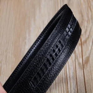 Vue macro d'une ceinture en cuir noir avec grain de litchi et détails de motif à damier