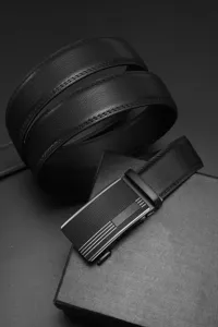 Détail d'une ceinture en cuir noir avec boucle automatique mate et boîte cadeau.