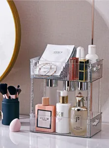 Elegant two-tier transparent acrylic cosmetic organizer shown in a vanity setting
