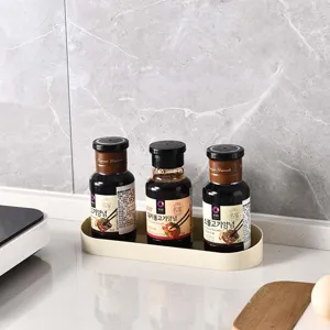 Beige oval kitchen storage tray holding three seasoning bottles on a marble countertop