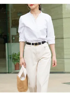 A close-up view of women's black genuine leather belt with gold round buckle on model