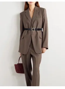 Elegant black leather belt with a gold D-ring buckle styled over a professional brown suit.