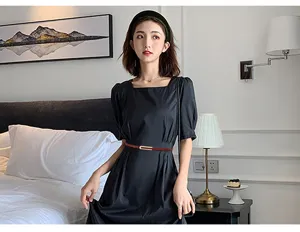 Cintura sottile in vera pelle marrone con fibbia dorata abbinata a un abito nero