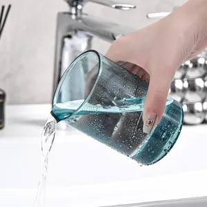 Transparante blauwe plastic tandenborstelbeker die water in een moderne wasbak giet