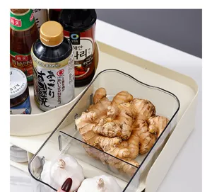 Transparent kitchen storage bin holding fresh ginger and garlic inside a larger organizer.