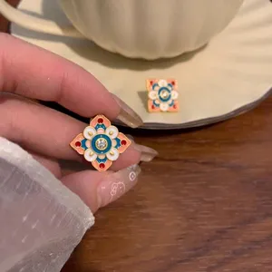 Dettaglio ravvicinato di orecchini vintage in smalto con motivo a nuvola.