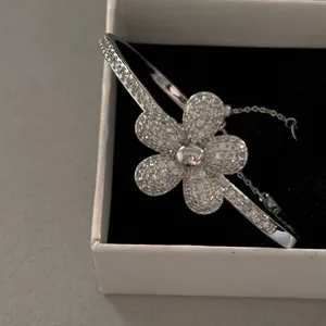 Macro detail of a sparkling silver flower bangle encrusted with pavé zircons in a gift box