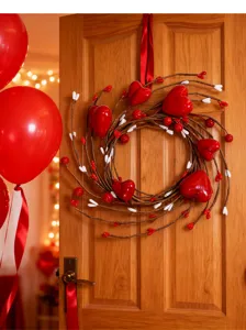 Artificial red heart berry wreath hung on a wooden door with festive red balloons