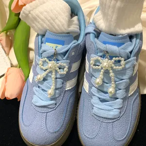 Elegant pearl bow shoe charms as decorative accessories on blue sneakers for a stylish look