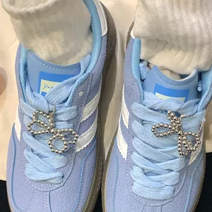 Macro view of elegant silver-beaded bow shoe charms attached to blue suede sneakers