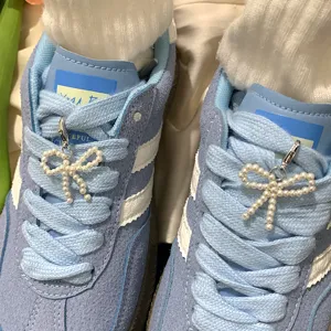 Detailed view of white pearl bow shoe charms clipped onto blue sneaker laces
