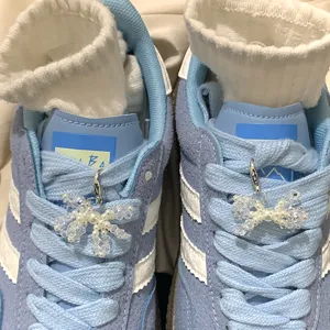 Detailed view of elegant pearl and crystal bow shoe charms on light blue sneakers.