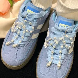 Close-up detail of elegant pearl bow shoe charms attached to blue suede sneaker laces